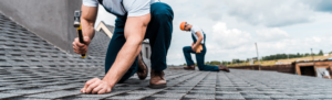 two men replacing shingles on roof